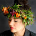 Model wearing a floral crown made or orange and pink flowers and greenery